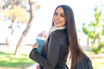 Young woman at outdoors holding a notebook with happy expression
