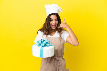 Young caucasian pastry chef woman with a big cake isolated on yellow background making phone...