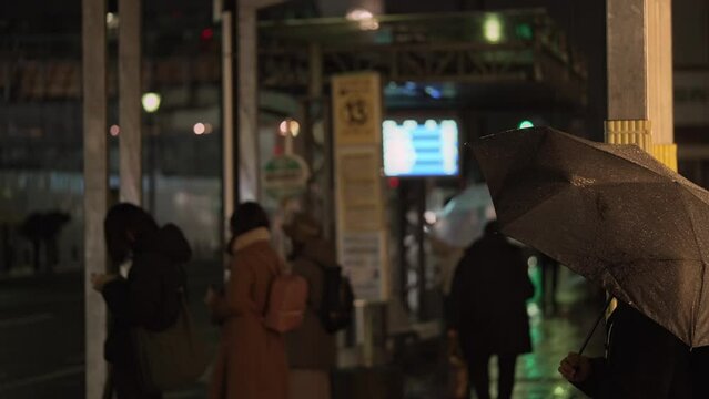 雨が降る夜,バス停で待機する人々