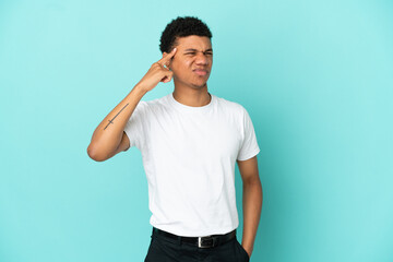 Young African American man isolated on blue background making the gesture of madness putting finger...