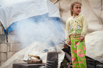A refugee woman and her daughter cook with wood. The tragic humanitarian conditions of Syrian...