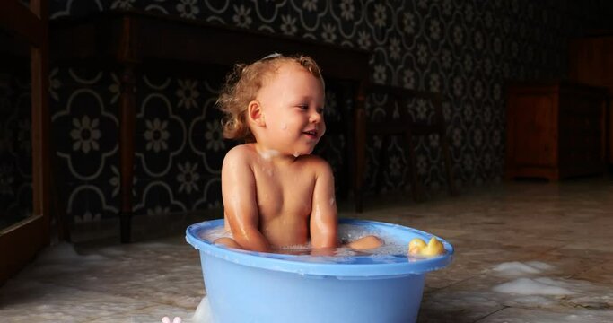 After some preparation, cheerful and mischievous baby delights in playful splashing, creating big splish of water with joy and excitement. Slow motion footage captures vibrant emotions
