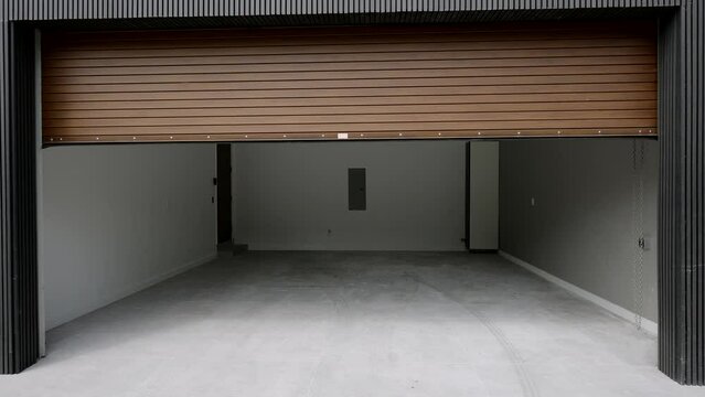 Exterior view of opening automatic garage door in modern high-tech suburban house. Contemporary technology for safety and comfortable living
