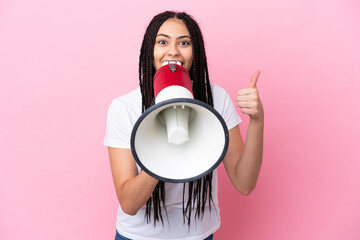 Teenager girl with braids over isolated pink background shouting through a megaphone to announce...