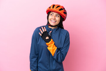Teenager cyclist girl isolated on pink background looking up while smiling