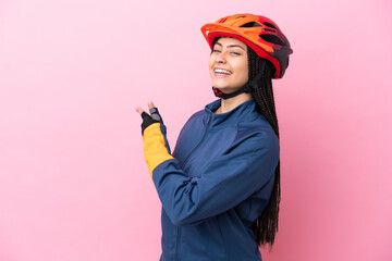 Teenager cyclist girl isolated on pink background pointing back - obrazy, fototapety, plakaty