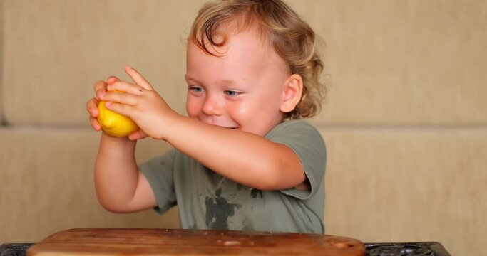Joyful and energetic baby boy gleefully tosses half lemons on floor, creating mess with his playful antics. His laughter fills kitchen as he explores and experiments with citrus fruit