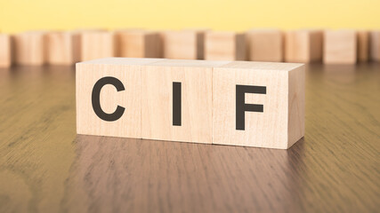 three wooden cubes on a yellow background, with the abbreviation CIF - Cost Insurance and Freight