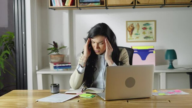 Tired transgender woman worker take short pause in online work to massage head to relax with closed eyes. Female employee overworked by pc feel fatigue 
