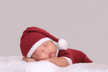 child in santa claus clothes sleeping on fluffy bed.
