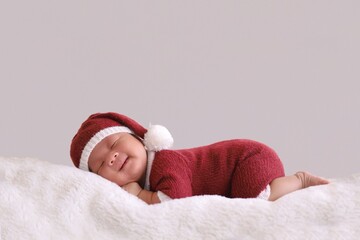 child in santa claus clothes sleeping on fluffy bed.