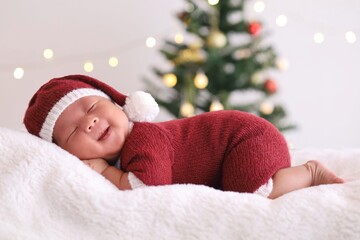 Obraz na płótnie Canvas child in santa claus clothes sleeping on fluffy bed.