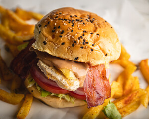 Grilled chicken breast sandwich with bacon, lettuce, onion rings and cheese served with a side of fries.