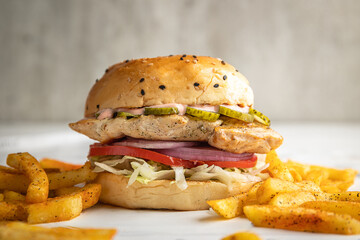 Chicken breast sandwich with mayonnaise, lettuce, ringed onion, pickle and tomato served with a...