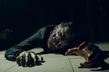 Zombie male creeps on floor halloween concept. Make up skin and blood face