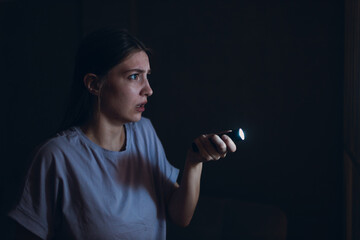 Woman scared holding hand flashlight in darkness and afraid of violence criminal robbery - obrazy, fototapety, plakaty