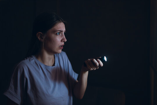 Woman scared holding hand flashlight in darkness and afraid of violence criminal robbery