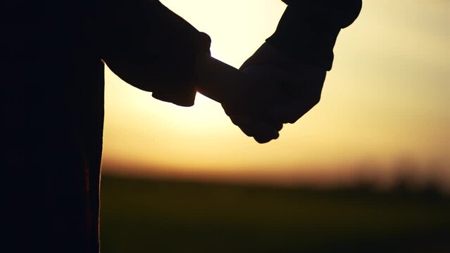 father holding her son hands. happy family kid dream concept. father take care of her daughter holding her hands at sunset in the park close-up. hands close-up lifestyle parent and daughter