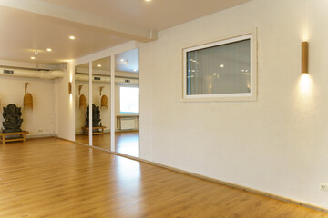 A spacious empty hall with columns and large windows. A gym with wooden floors for yoga and fitness...