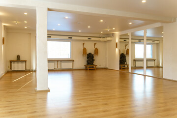 A spacious empty hall with columns and large windows. A gym with wooden floors for yoga and fitness...