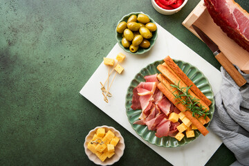 Slices of prosciutto or jamon. Delicious grissini sticks with prosciutto, cheese, rosemary, olives...