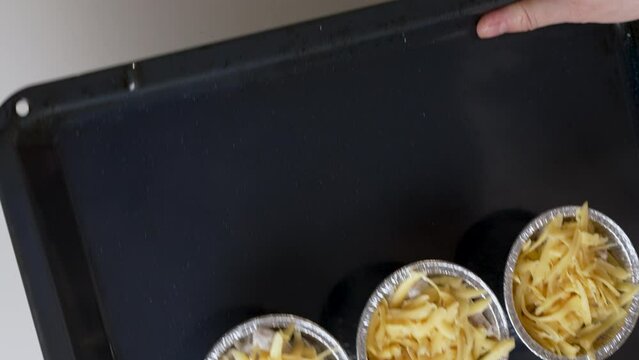 Julienne recipe baked with champignons and chicken in a creamy sauce, step-by-step preparation. Nutrition concept. Chef puts food into oven, tartlets in home kitchen.Vertical shot