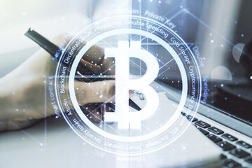 Creative Bitcoin concept with hand writing in notebook on background with laptop. Multiexposure