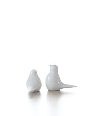 pair of white Decorative porcelain birds figurine close up on abstract light background. small statuette of ceramic for decoration interior. symbol of family, love, romance. element for design.