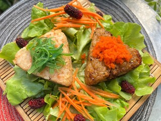 Triangular rice balls topped with seaweed and shrimp roe with salad and mulberry