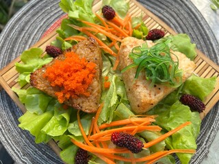 Triangular rice balls topped with seaweed and shrimp roe with salad and mulberry