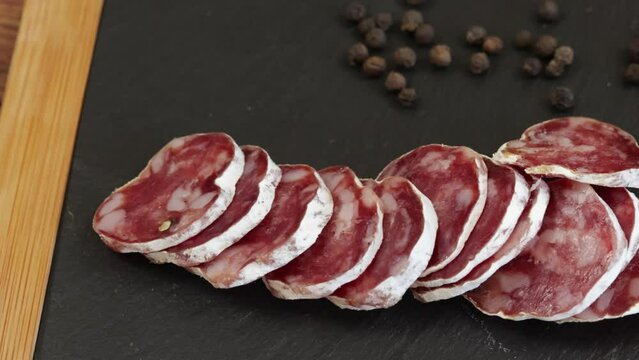 saucisson sec tranch&eacute; sur une planche &agrave; d&eacute;couper