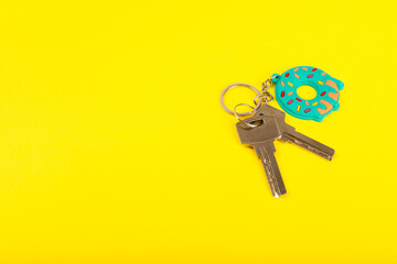 Keychain in the shape of a donut with a key ring on a yellow background. Concepts for real estate...