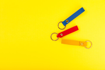 Leather keychain with a key ring on a yellow background. Concepts for real estate and moving home or renting property. Buying a property. Mock-up keychain.Copy space.