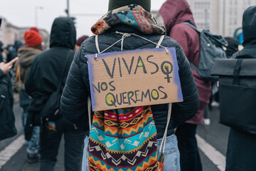 Día Internacional de la mujer, persona irreconocible con una pancarta en la espalda escrita Vivas...
