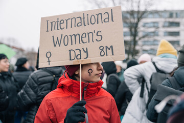 Teenage girl holding a banner for International Women's Day