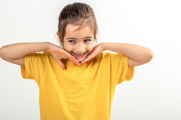 Portrait little girl keeping hands near face, smiling isolated on white.