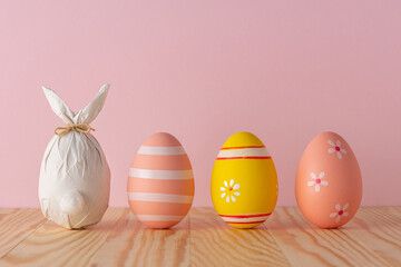 Easter egg wrapped in a paper in the shape of a bunny with colorful Easter eggs. Minimal Easter background. Spring holidays concept.