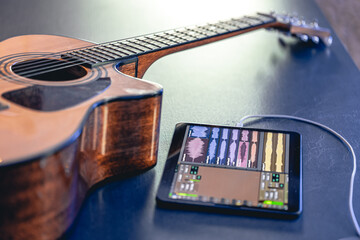 Acoustic guitar and tablet on the table, music recording concept.