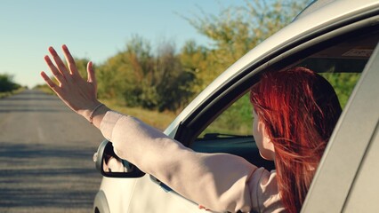 girl rides car with her hand out window, summer day, woman with hair enjoying trip, looking...