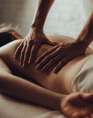 Hands of female chiropractor massaging shoulders of young woman lying on massage table. Concept of...