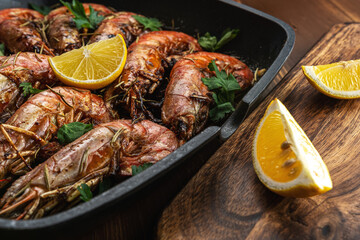 Fried shrimps on grill pan with fresh herbs and lemon slice. Seafood background.
