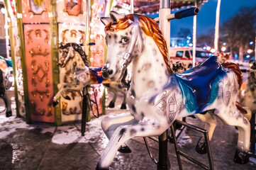 Carousel horses at the fairground in the evening. Christmas and New Year background