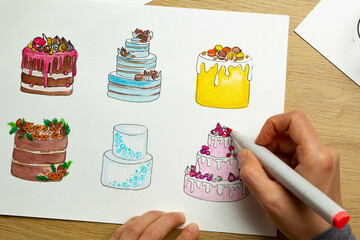 The designer draws designs on paper for cakes.