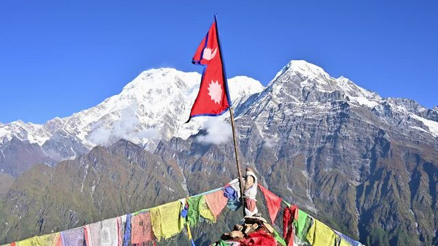 Nepali flag with beautiful view of Mt.Annapurna South (7,219 m) and Mt.Hiunchuli (6,441 m) seen from Mardi Himal view point in the Annapurna region of Nepal.
