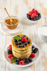 Delicious pancakes with fresh berries on white wooden table. Food concept.
