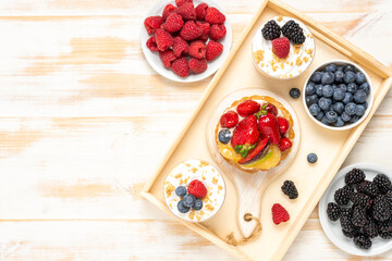 Sweet desserts with fresh berries on wooden background.