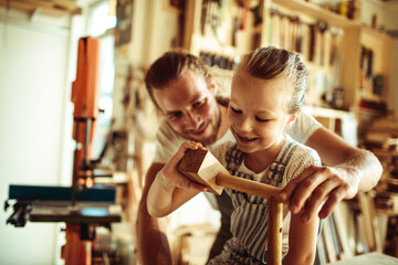 Father and Daughter Enjoying Woodworking Together in a Sunny Workshop