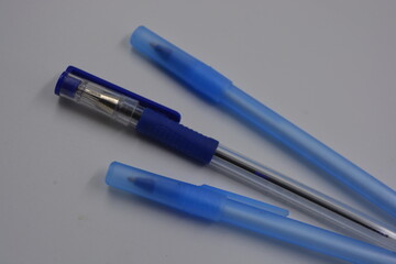 Stationery, office stationery, two plastic blue pens and one pen blue cap are arranged on a white...