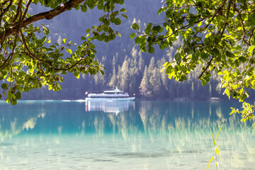 Passenger ferry boat gliding along east bank of alpine lake Weissensee, Carinthia, Austria....