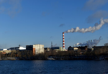 Fototapeta premium The smoking pipe of a thermal power plant and a reservoir. The urban landscape in Yekaterinburg.